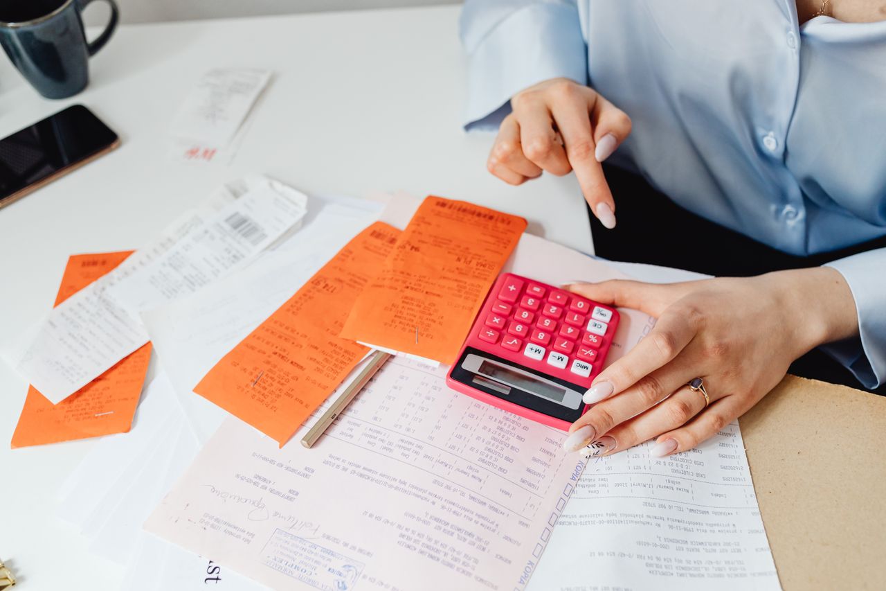heros-img Businesswoman calculates expenses using receipts and calculator at desk. Ideal for finance, accounting themes.