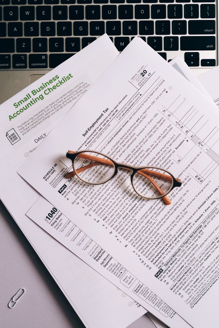 The Art of Drawing Readers In: Your attractive post title goes here Overhead view of tax documents and eyeglasses on a laptop keyboard, ideal for finance or accounting themes.