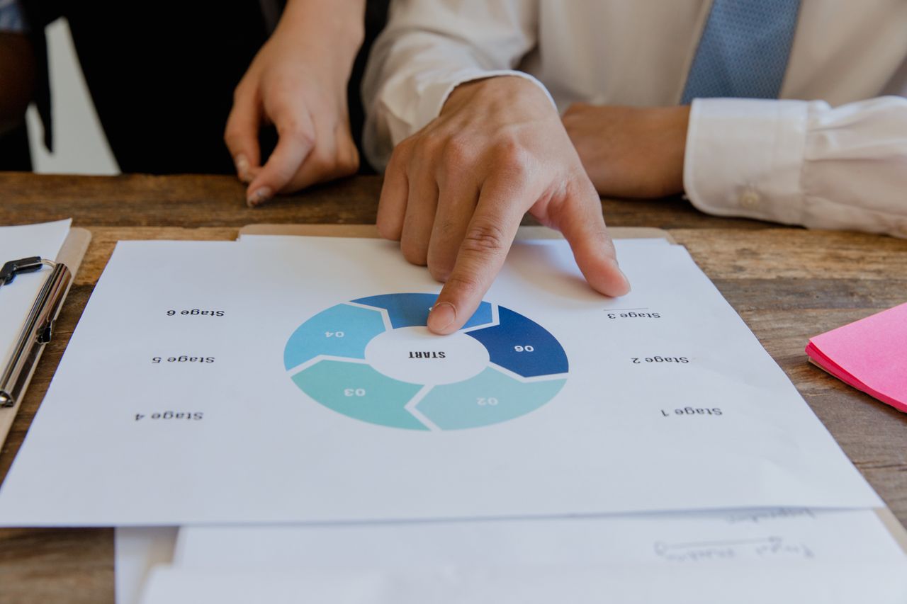 services-03 Close-up of hands pointing to a circular business strategy plan on paper.